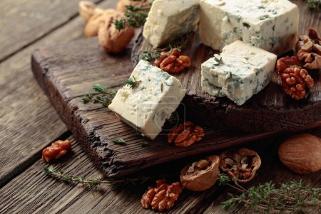 Photo for Blue cheese with walnuts and thyme on an old wooden table. - Royalty Free Image