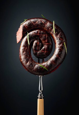 Photo for Spanish black pudding or blood sausage with rosemary on a black background. - Royalty Free Image