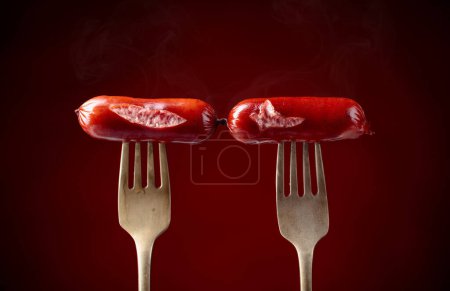 Photo for Grilled sausages on a forks. Dark red background, copy space. - Royalty Free Image