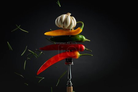 Photo for Hot chili peppers with garlic and rosemary on a fork. Concept of spicy food. - Royalty Free Image