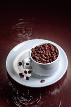 Téléchargez les photos : White cup with coffee beans on a brown background with water ripples. Coffee concept. Copy space. - en image libre de droit