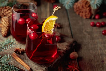 Photo for Christmas drink with spices, orange, and cranberries on an old wooden table. - Royalty Free Image