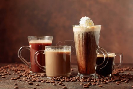 Téléchargez les photos : Diverses boissons au café et au chocolat avec des grains de café éparpillés sur un fond brun. Espace de copie. - en image libre de droit