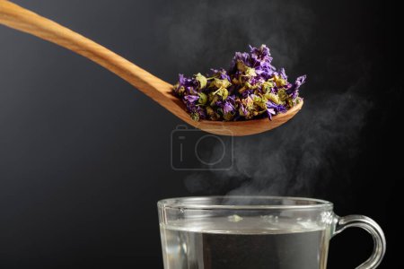 Foto de Flores secas de malva para hacer té de hierbas y taza con agua caliente. - Imagen libre de derechos