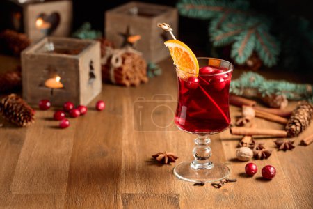 Foto de Bebida caliente de Navidad con rodajas de naranja. Clavos, nueces, arándanos, canela y anís están esparcidos en una vieja mesa de madera. - Imagen libre de derechos