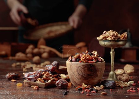 Photo for Various dried fruits and nuts are in a wooden bowl on a kitchen table. Selective focus. - Royalty Free Image