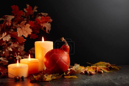Photo for Still life with pumpkin, dried-up leaves, burning candles, and oak branches. Black background with copy space. Autumn concept. - Royalty Free Image