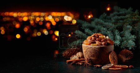 Photo for Christmas still-life with dried fruits, nuts, spruce branches, and burning candles on a background of night city. Copy space. - Royalty Free Image