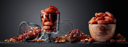 Photo for Dates, dried fruits, berries, nuts, and seeds on a black background. Copy space. - Royalty Free Image