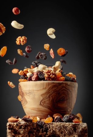 Téléchargez les photos : Voler des fruits secs et des noix. Le mélange de noix séchées et de raisins secs dans un bol en bois. - en image libre de droit