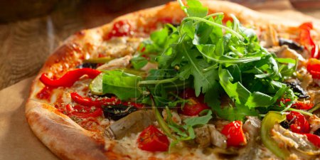 Foto de Sabrosa pizza vegetariana recién horneada con tomates, aceitunas, pimentón y rúcula fresca. Enfoque selectivo. - Imagen libre de derechos