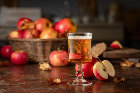 Cidre de pomme aux pommes sur une vieille table de cuisine.
