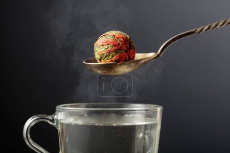 Téléchargez les photos : Boule de thé vert chinoise au jasmin et fleurs de souci (calendula), prête à être préparée. Thé vert et tasse à l'eau chaude. - en image libre de droit