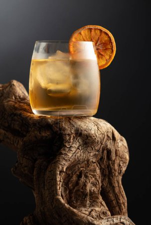 Foto de Cóctel a la antigua con hielo y rebanada de naranja seca en un viejo enganche de madera. - Imagen libre de derechos