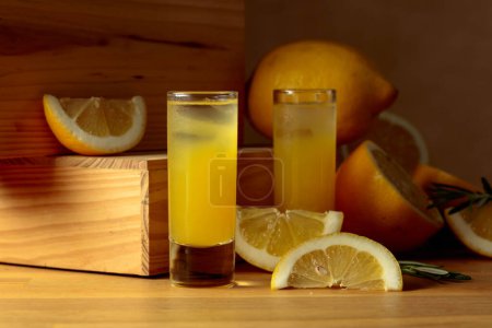 Foto de Licor de limón tradicional limoncello y cítricos frescos sobre una mesa de madera. - Imagen libre de derechos