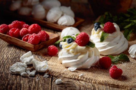 Photo for Dessert Pavlova with raspberries, blueberries and mint on a old wooden table. - Royalty Free Image