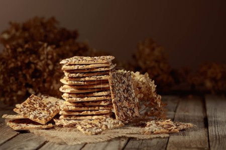 Foto de Crispy crackers with sunflower and flax seeds on an old wooden table. Simple healthy food. Copy space. - Imagen libre de derechos