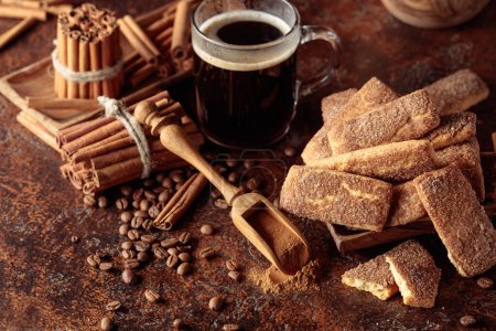 Téléchargez les photos : Biscuits à la cannelle sucrés et une tasse de café noir sur un fond vintage marron. - en image libre de droit
