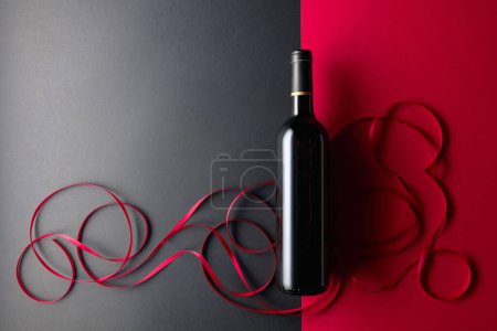 Foto de Bottle of red wine with red satin ribbons. Top view. - Imagen libre de derechos