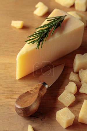 Téléchargez les photos : Parmesan cheese with rosemary and knife on a wooden cutting board. - en image libre de droit
