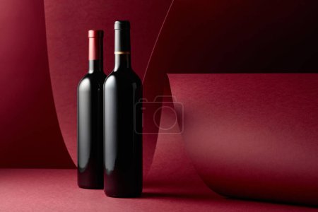 Téléchargez les photos : Bouteilles de vin rouge sur fond rouge. Espace de copie. - en image libre de droit