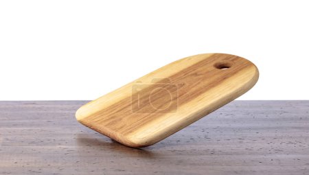 Photo for Cutting board falling on an old wooden table. Food preparation. Culinary background. Empty wooden cutting board, product display space. - Royalty Free Image