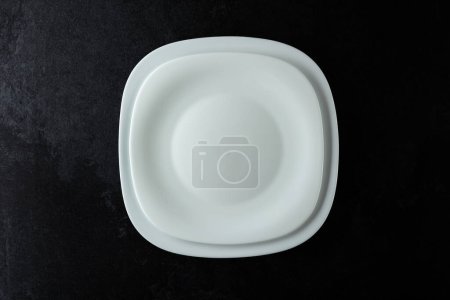 Foto de Platos blancos vacíos en una mesa de piedra negra. Vista superior, espacio de copia. - Imagen libre de derechos
