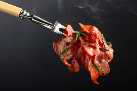 Foto de Rebanadas de tocino frito caliente con romero en un tenedor. Copiar espacio. - Imagen libre de derechos