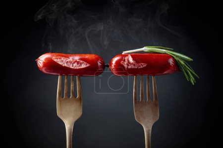 Téléchargez les photos : Saucisses grillées au romarin sur une fourchette. Fond noir, espace de copie
. - en image libre de droit