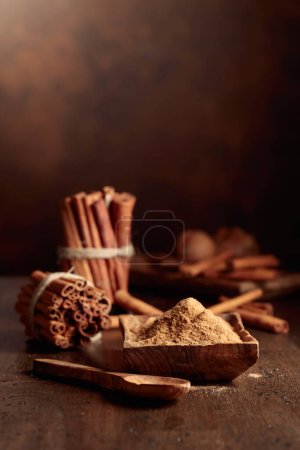 Foto de Palitos de canela y polvo en una vieja mesa de madera. Copiar espacio. - Imagen libre de derechos