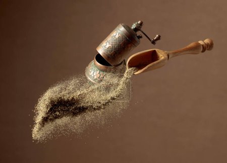 Photo for Pepper powder is poured out of the wooden spoon. Old copper pepper grinder and a wooden spoon with pepper ground. Copy space. - Royalty Free Image