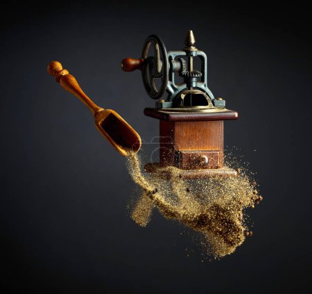 Photo for Pepper powder is poured out of the wooden spoon. Old pepper grinder and a wooden spoon with pepper ground. - Royalty Free Image