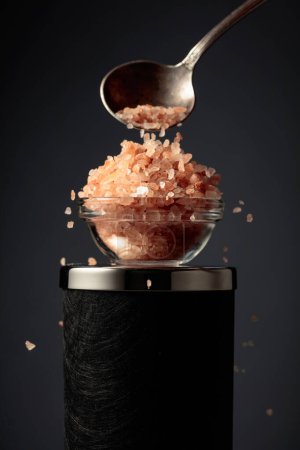 Téléchargez les photos : Le sel rose est versé dans un petit bol en verre. - en image libre de droit