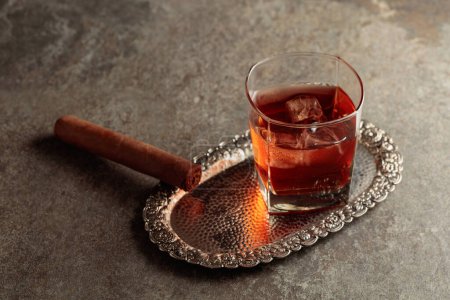 Foto de Whisky con hielo y cigarro en una vieja mesa de piedra. Copiar espacio. - Imagen libre de derechos