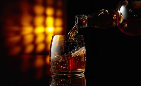 Photo for Pouring whiskey into a glass on a black background. Copy space. - Royalty Free Image