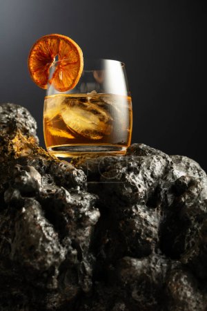 Téléchargez les photos : Cocktail à l'ancienne avec glace et tranche d'orange séchée sur une pierre grise. - en image libre de droit