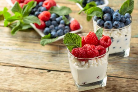 Téléchargez les photos : Dessert caillé à la crème, framboises et bleuets garnis de menthe fraîche. - en image libre de droit