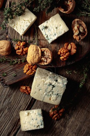 Photo for Blue cheese with walnuts and thyme on an old wooden table. Top view. - Royalty Free Image