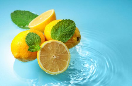 Photo for Ripe juicy lemons with mint on a blue background with water splashes. Copy space. - Royalty Free Image