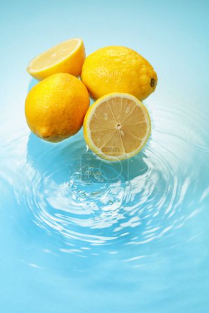 Téléchargez les photos : Ripe juicy lemons on a blue background with water splashes. Copy space. - en image libre de droit