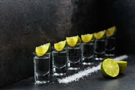 Foto de Tequila with lime and sea salt on a background of black slate. - Imagen libre de derechos
