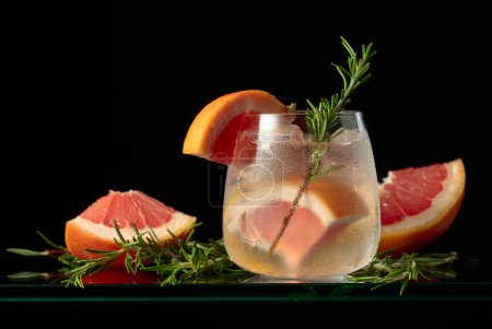 Téléchargez les photos : Gin tonique au cocktail avec glace, pamplemousse et romarin dans un verre congelé. - en image libre de droit
