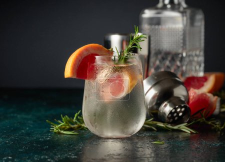 Foto de Cóctel gin tonic con hielo, pomelo y romero. Bebida refrescante con hielo natural en un vaso congelado. - Imagen libre de derechos