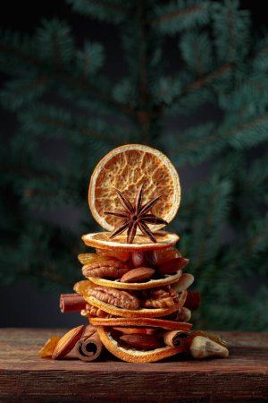 Téléchargez les photos : Fruits secs et noix sur une vieille table en bois. Nature morte de Noël avec des branches d'épinette. Espace de copie. - en image libre de droit