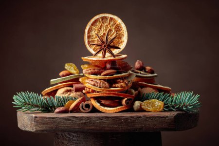 Foto de Frutas secas y frutos secos sobre una vieja mesa de madera. Bodegón de Navidad con ramas de abeto. - Imagen libre de derechos