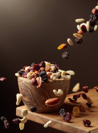 Photo for Flying dried fruits and nuts. The mix of nuts and dried berries are in a wooden bowl. - Royalty Free Image