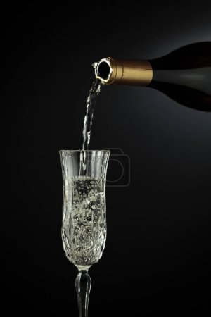 Foto de El vino espumoso se vierte de una botella en un vaso. Copiar espacio. - Imagen libre de derechos