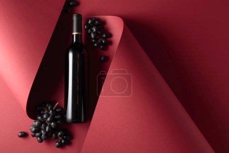 Téléchargez les photos : Bouteille de vin rouge et raisins bleus. Copier l'espace pour votre texte, vue du dessus. - en image libre de droit