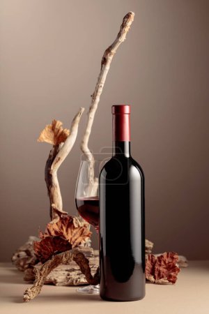 Photo for Bottle and glass of red wine with a composition of old wood. Minimalistic composition on a beige background for product branding, identity, and packaging. Copy space. - Royalty Free Image