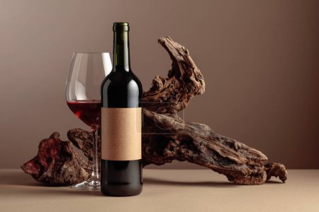 Photo for Bottle and glass of red wine. On a bottle old empty label. In the background old weathered snag. Frontal view with copy space. - Royalty Free Image